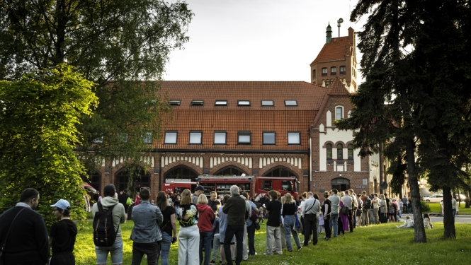 Fonā muzejs. Cilvēki stāv rindā, lai iekļūtu Latvijas Ugunsdzēsības muzejā. 