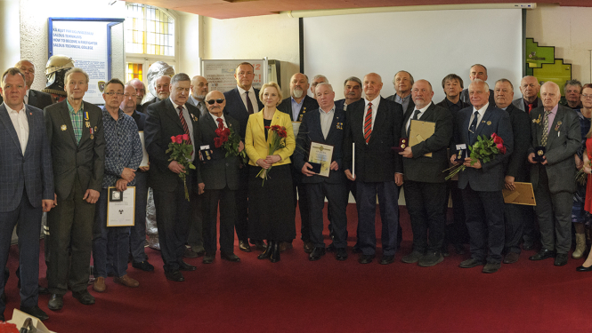 Pasākuma dalībnieku kopbilde Latvijas Ugunsdzēsības muzeja Slavas zālē. 