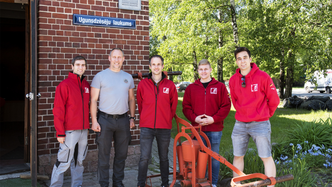 Pie muzeja ieejas durvīm  pieci ugunsdzēsēji civilapģērbā