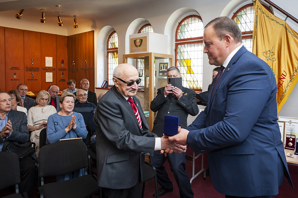 Iekšlietu ministrs Rihards Kozlovskis pasniedz piemiņas zīmi Černobiļas AES seku likvidēšanas dalībniekam. Fonā sanākušie pasākuma dalībnieki. 