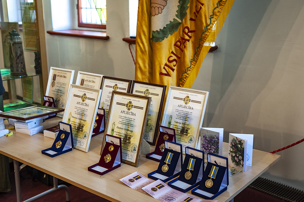 Uz galda izkārtotas piemiņas zīmes un atzinības raksti, kas tika pasniegti Černobiļas AES seku likvidēšanas dalībniekiem.