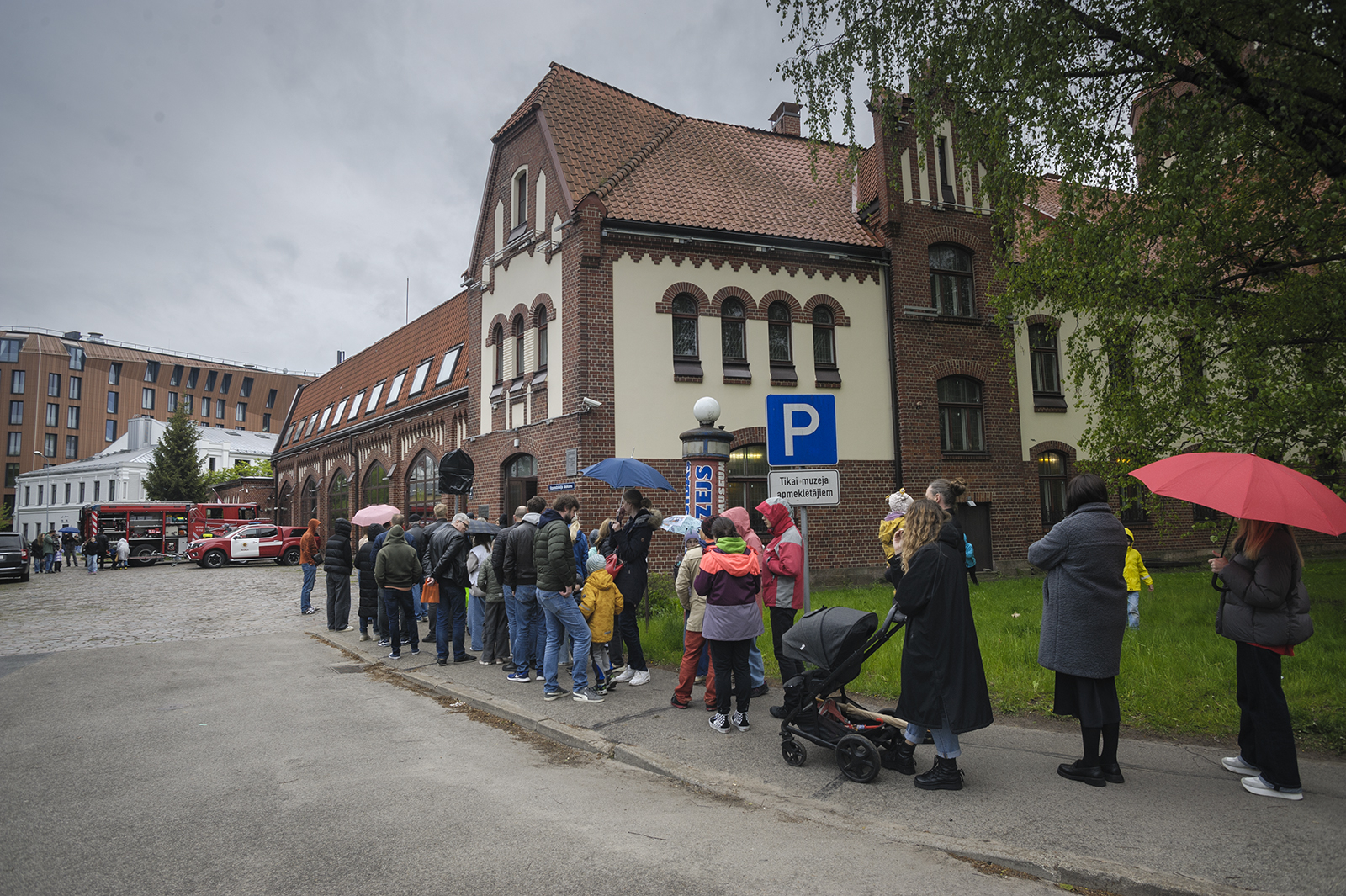 Cilvēki stāv  rinda pie muzeja ēkas