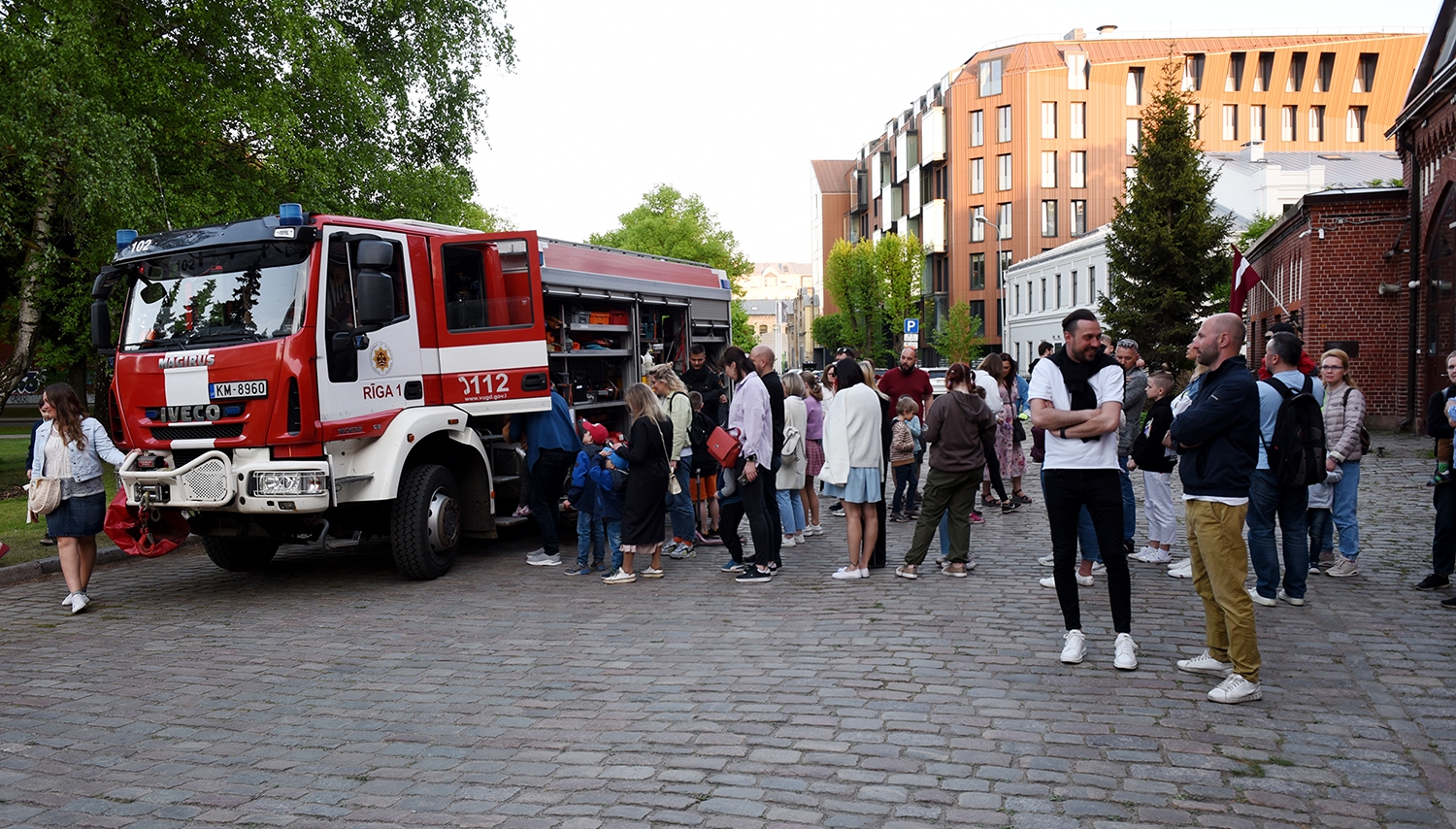 Apmeklētāji aplūko ugunsdzēsēju automašīnu laukumā pie muzeja 