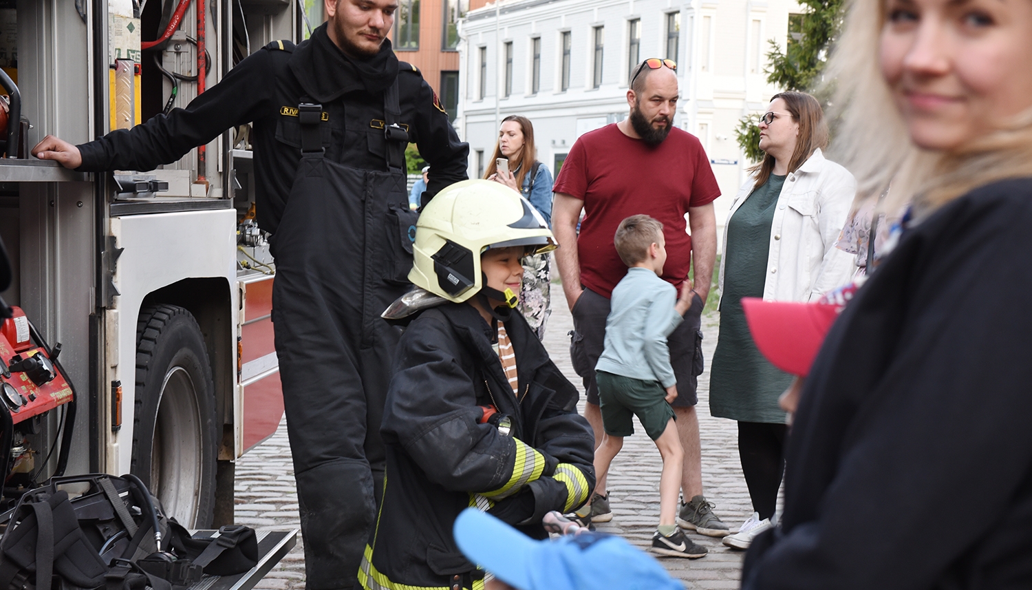 Mazis ugunsdzēsējs pie ugunsdzēsības automašīnas laukumā pie muzeja