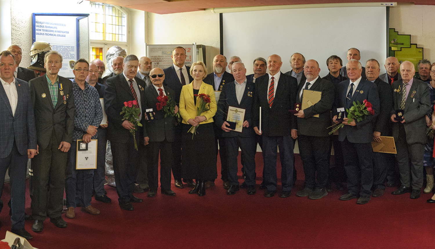 Pasākuma dalībnieku kopbilde Latvijas Ugunsdzēsības muzeja Slavas zālē. 