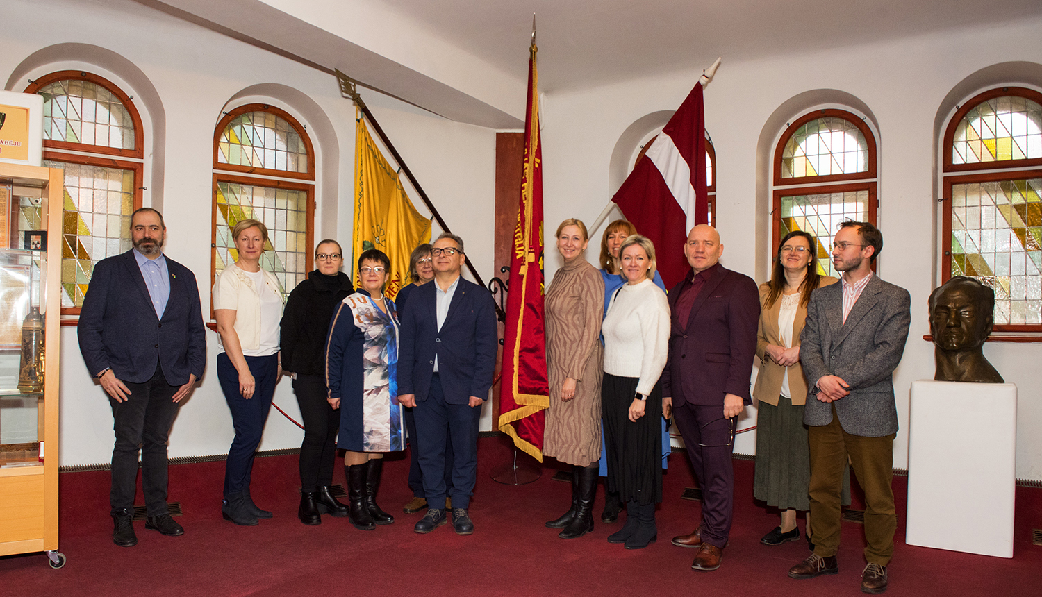 Kopbilde Valsts kancelejas darbinieki un VUGD vadība muzeja Slavas zālē, fonā trīs karogi