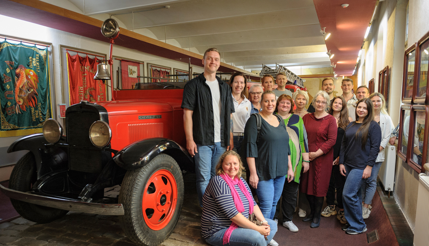 Pārvaldes kolektīvs Vēstures zēlē pie ugunsdzēsības automašīnas